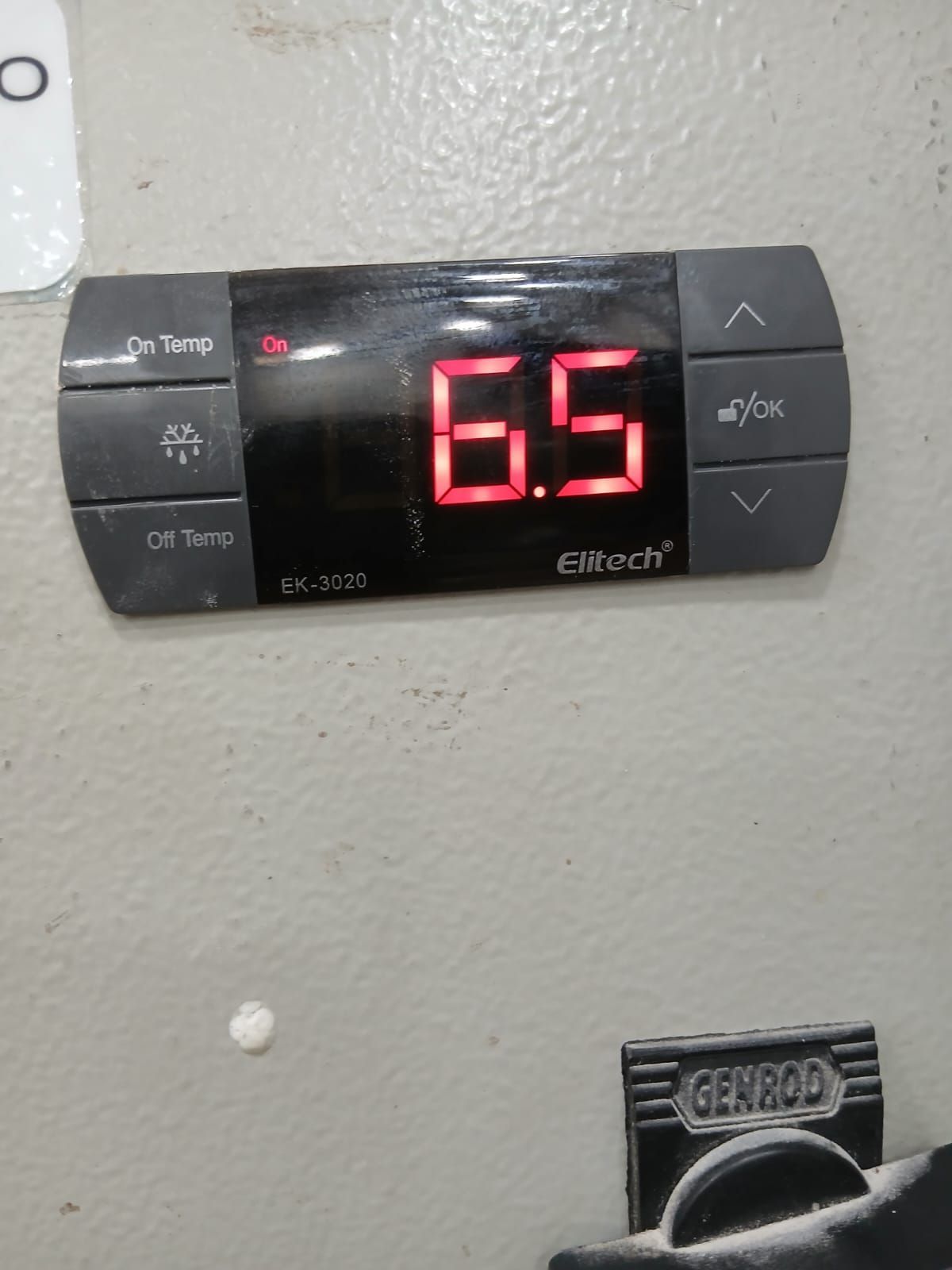Un controlador de temperatura digital Elitech montado en la pared muestra una lectura roja de 6,5.