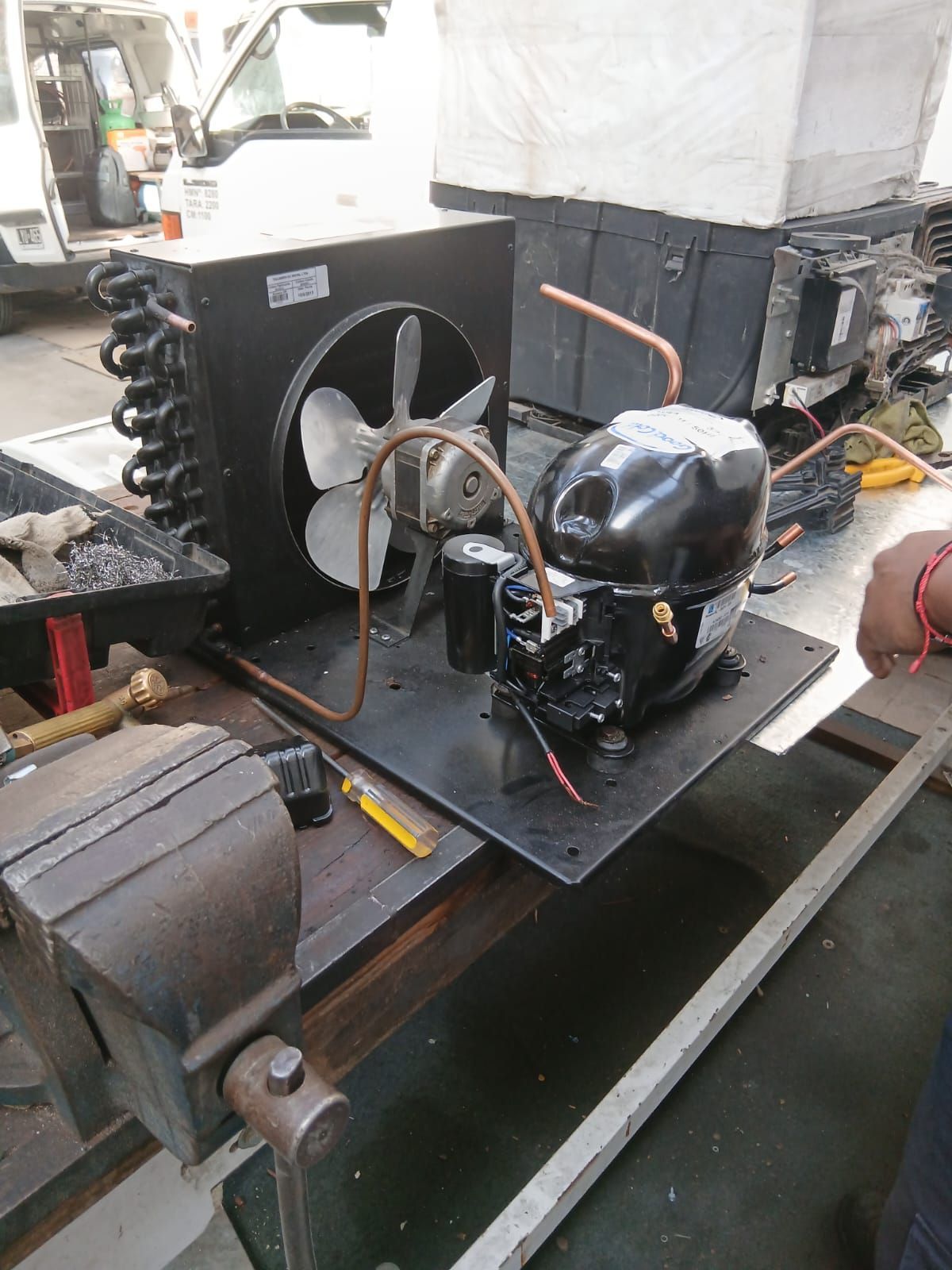 Una pequeña unidad compresora de refrigeración con un ventilador condensador, tubos de cobre.