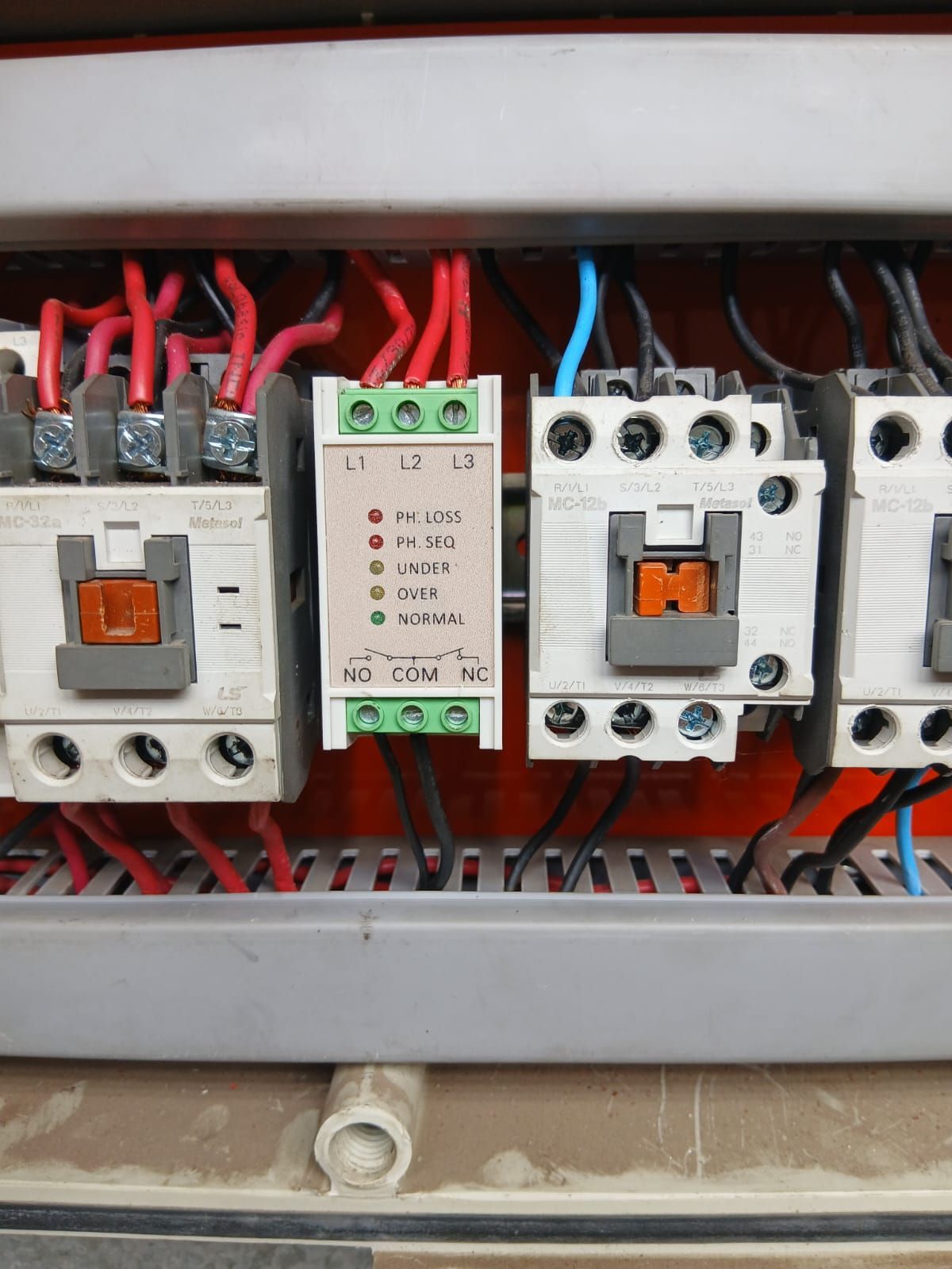 Panel de control eléctrico con tres contactores industriales y un relé central de monitorización de fase.