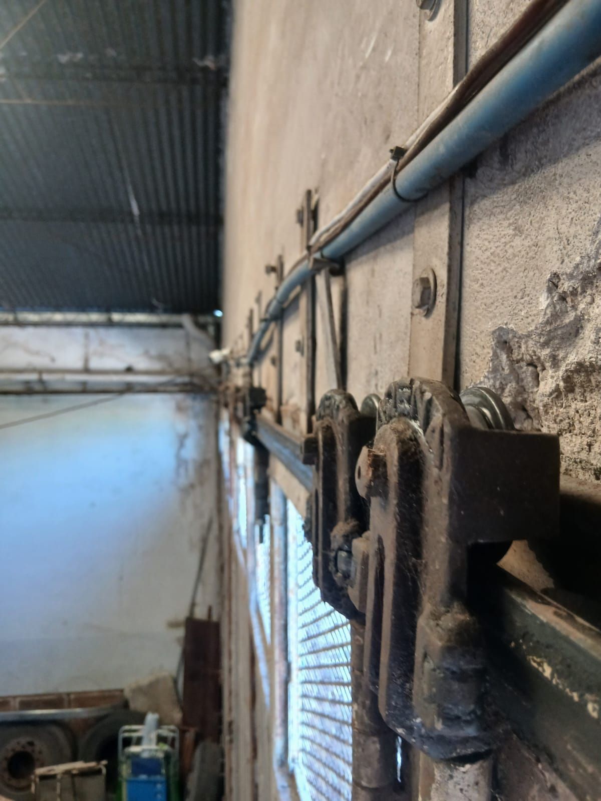 Primer plano de un mecanismo de herrajes para puerta corredera industrial de alta resistencia montado en una pared.