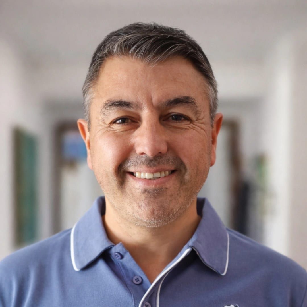 Una persona sonriente, de pelo corto y oscuro, que viste una camisa polo azul claro con ribetes blancos.