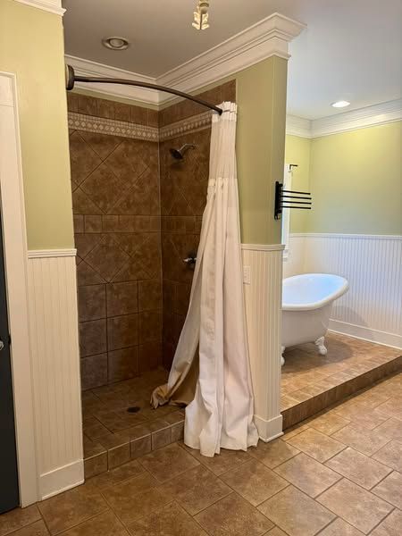 Bathroom with a shower and a clawfoot tub on a raised platform, light green walls, and beige tiled floor.