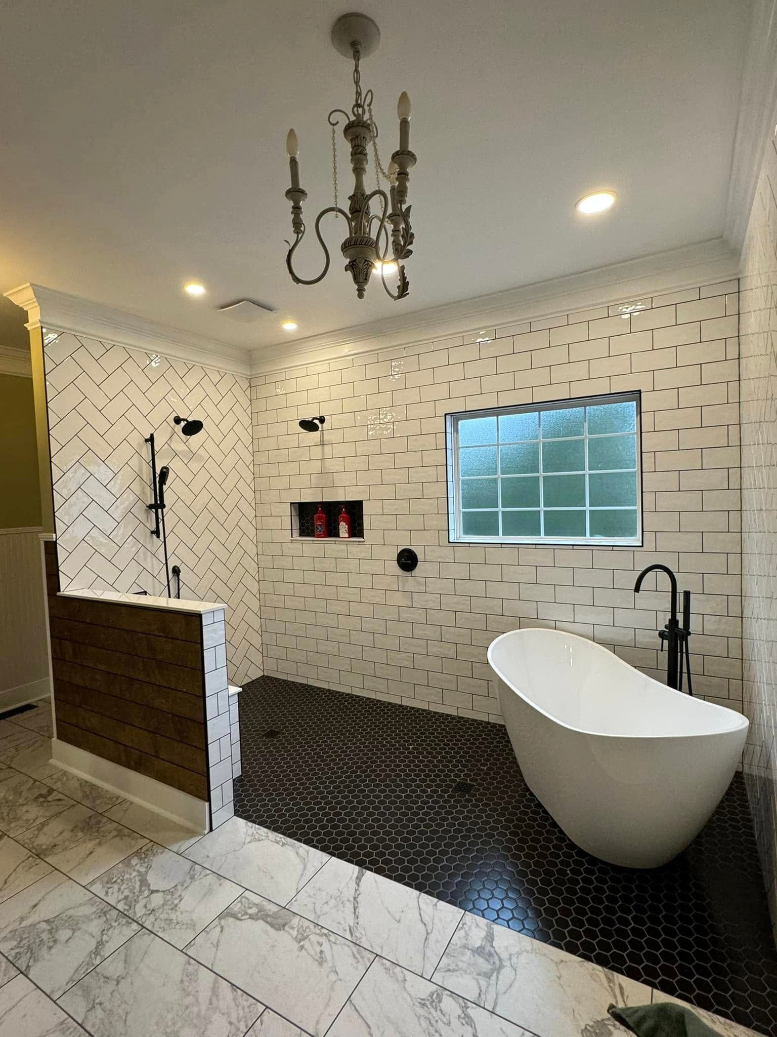 Elegant bathroom with white tub, black tile floor, patterned walls, and chandelier.