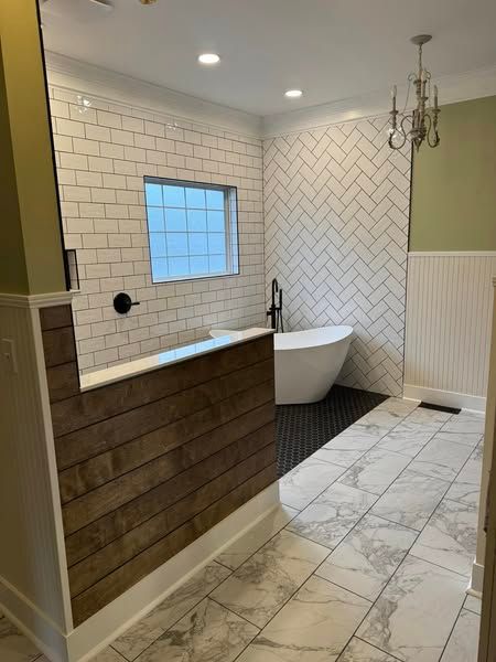 Bathroom with white subway tile, a freestanding tub, and wood paneling.