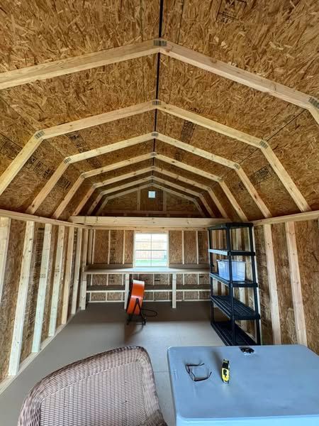 Interior view of a wooden shed with a workbench, shelves, and a small window.