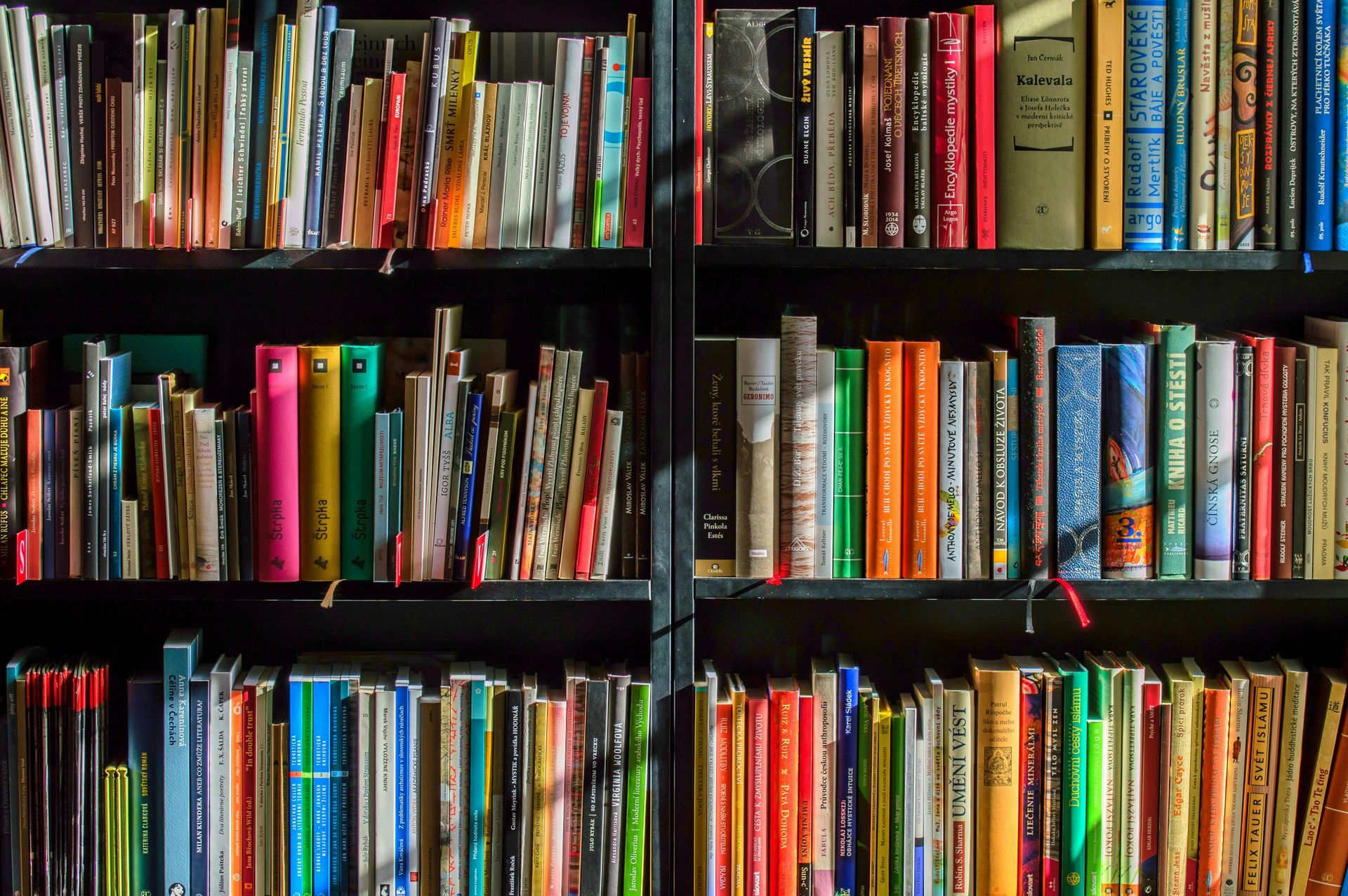 Uma estante cheia de livros coloridos.
