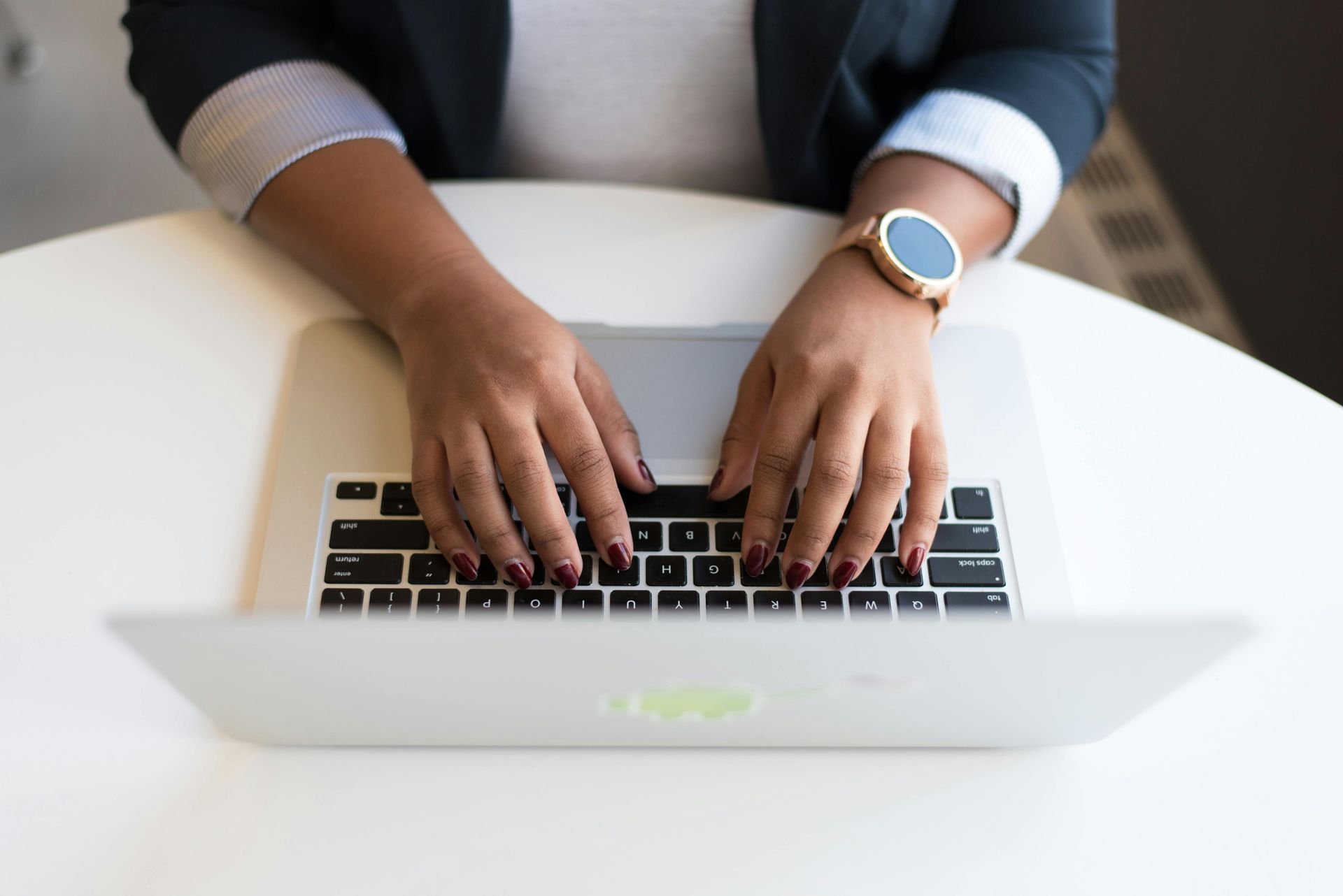 Uma mulher está digitando em um laptop enquanto usa um relógio.