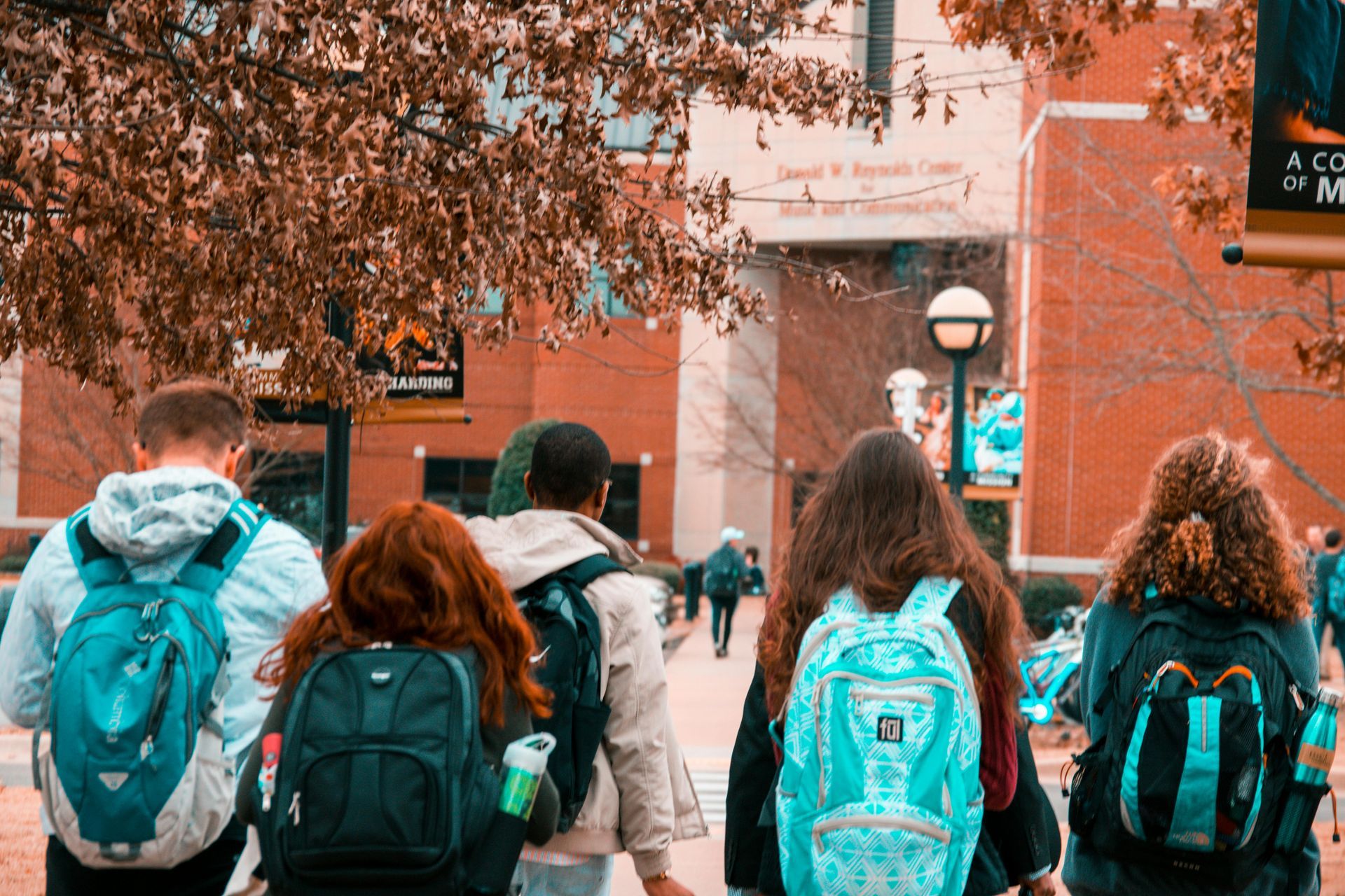 Um grupo de estudantes com mochilas está caminhando pela calçada.