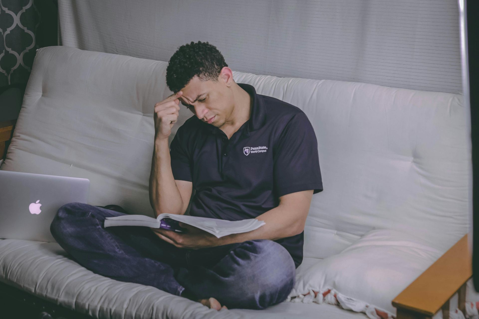 Homem sentado no sofá estudando com uma feição preocupada