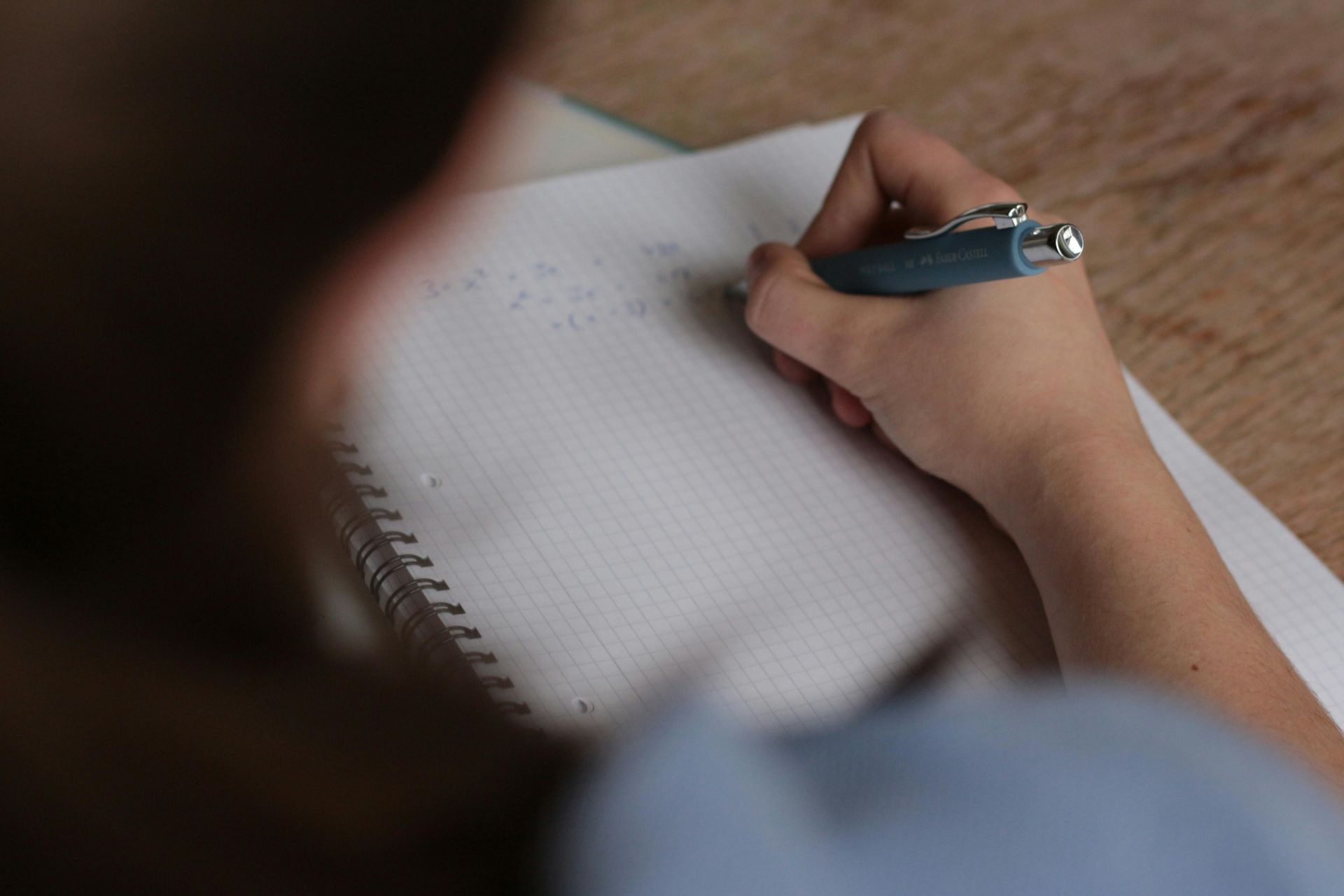 Uma pessoa está escrevendo em um caderno com uma caneta.