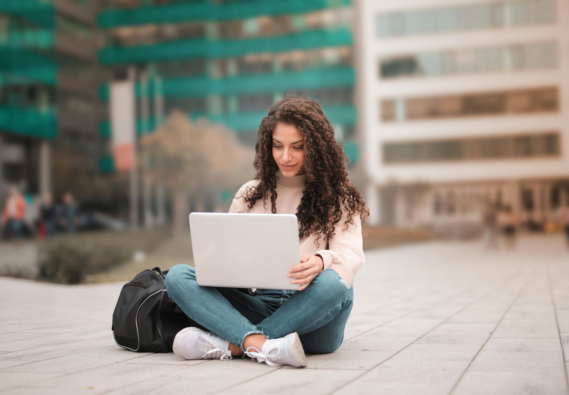 Mulher sentada em um parque com um computador no colo estudando