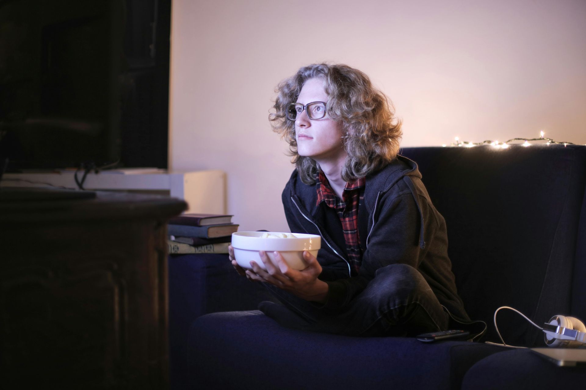 Pessoa assistindo filme sentada no sofá e segurando uma vasilha com pipoca