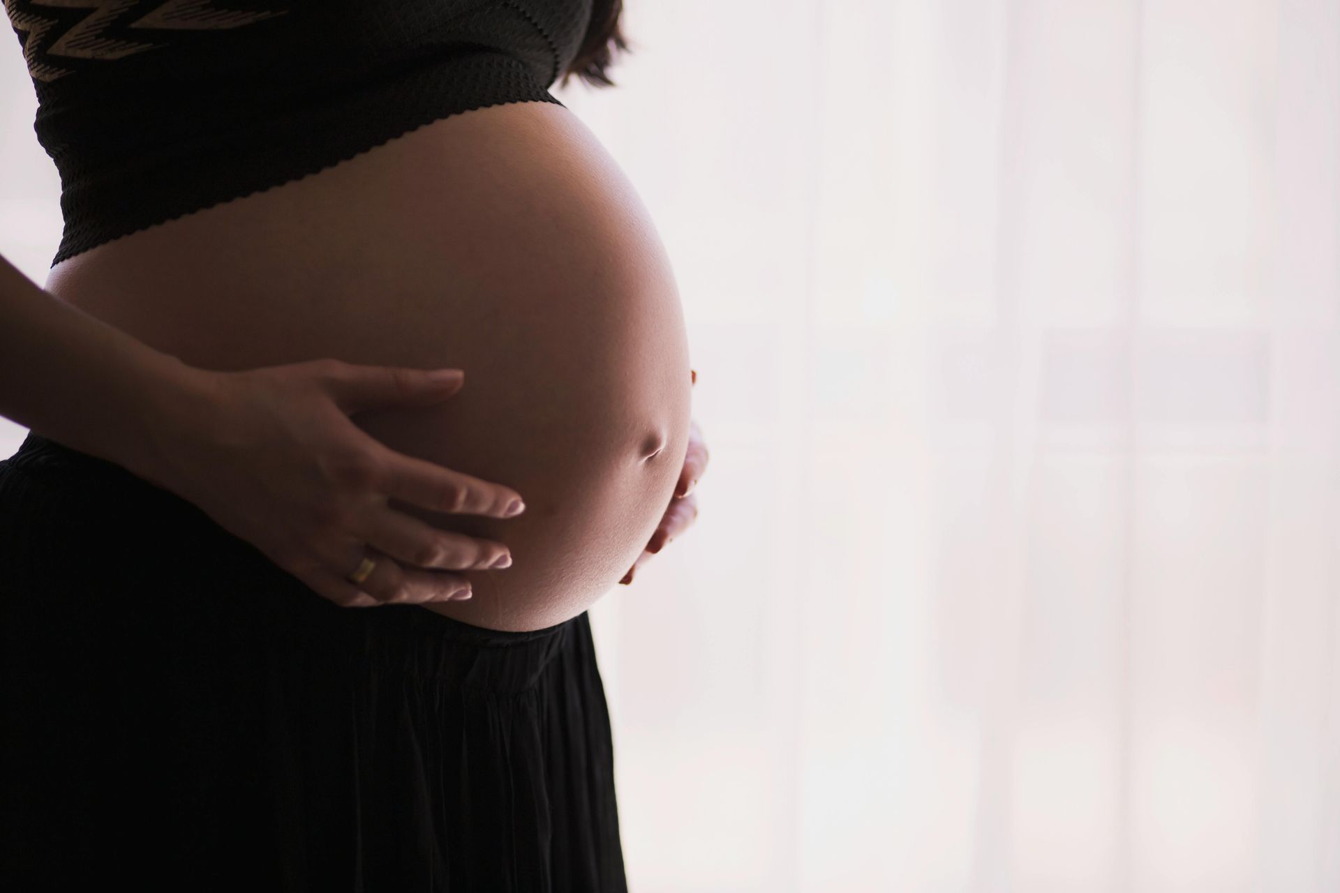 Mulher grávida com as duas mãos na barriga