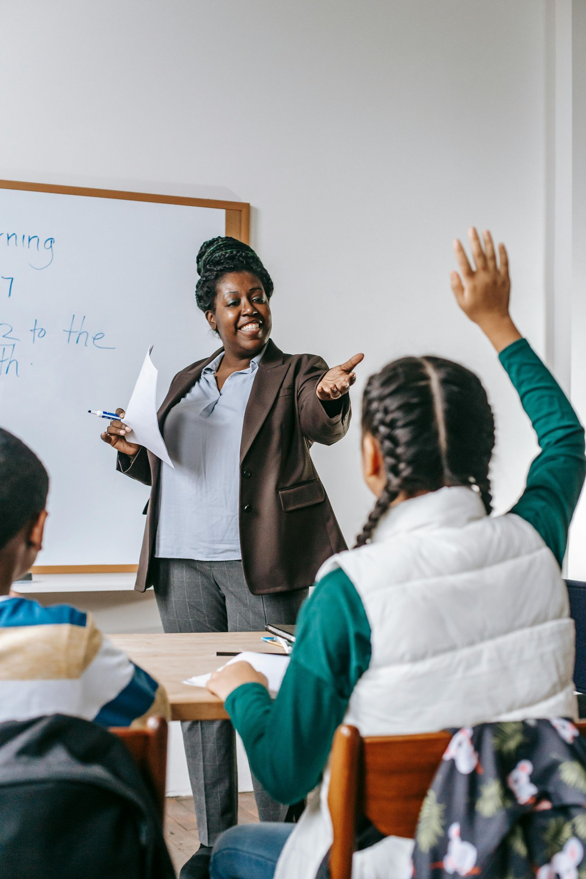 Uma professora está fazendo uma pergunta aos seus alunos em uma sala de aula.