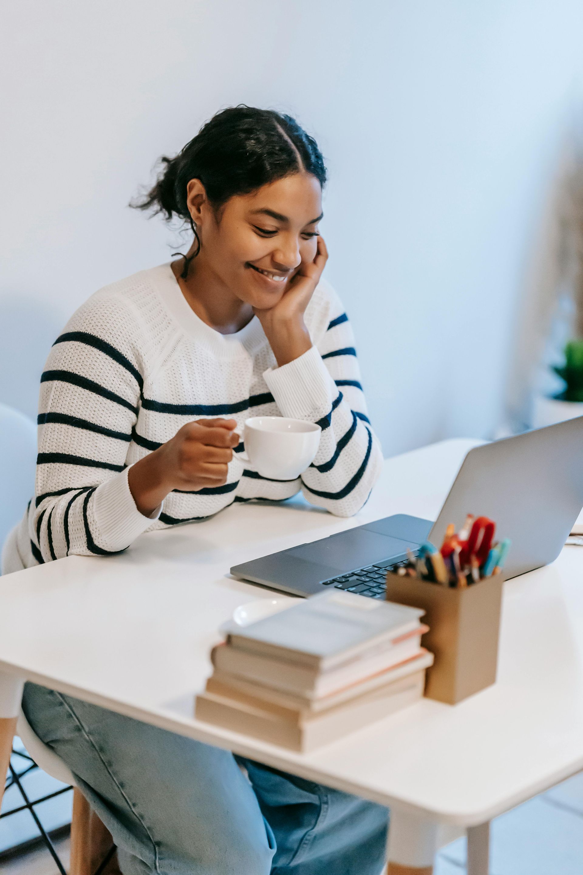 Mulher sentada em frente ao computador estudando e sorrindo