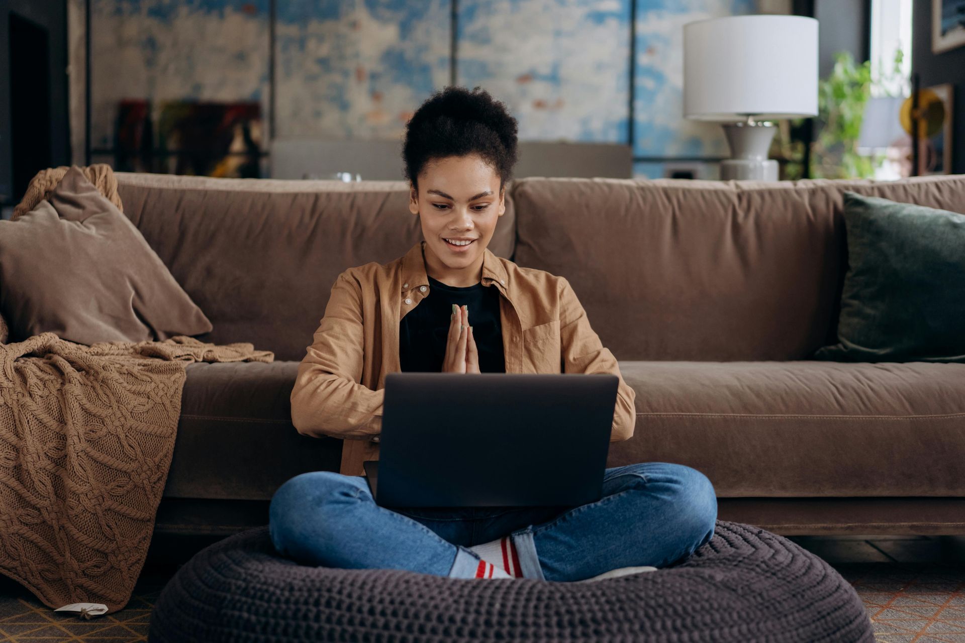 A woman is sitting on a couch using a laptop computer.