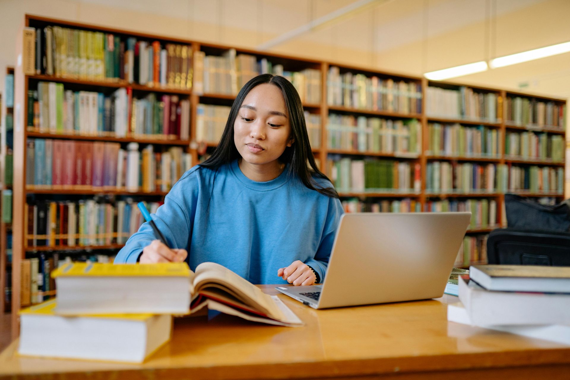 Mulher sentada em uma mesa da biblioteca e estudando