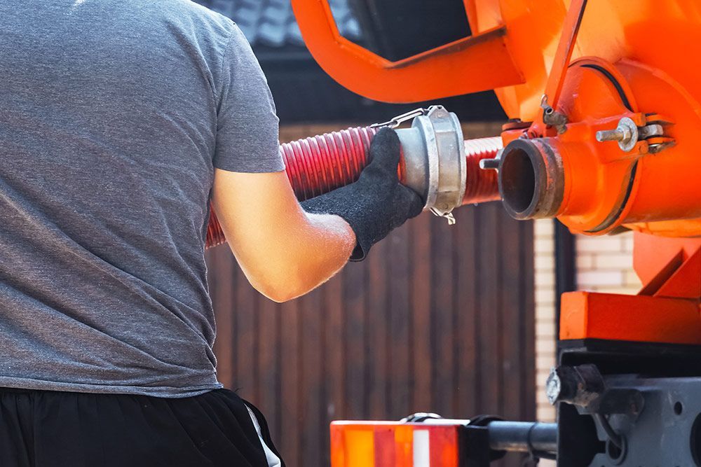 A Man is Holding a Hose Attached to a Vacuum Truck — Liquid Waste Disposal in Port Macquarie, NSW