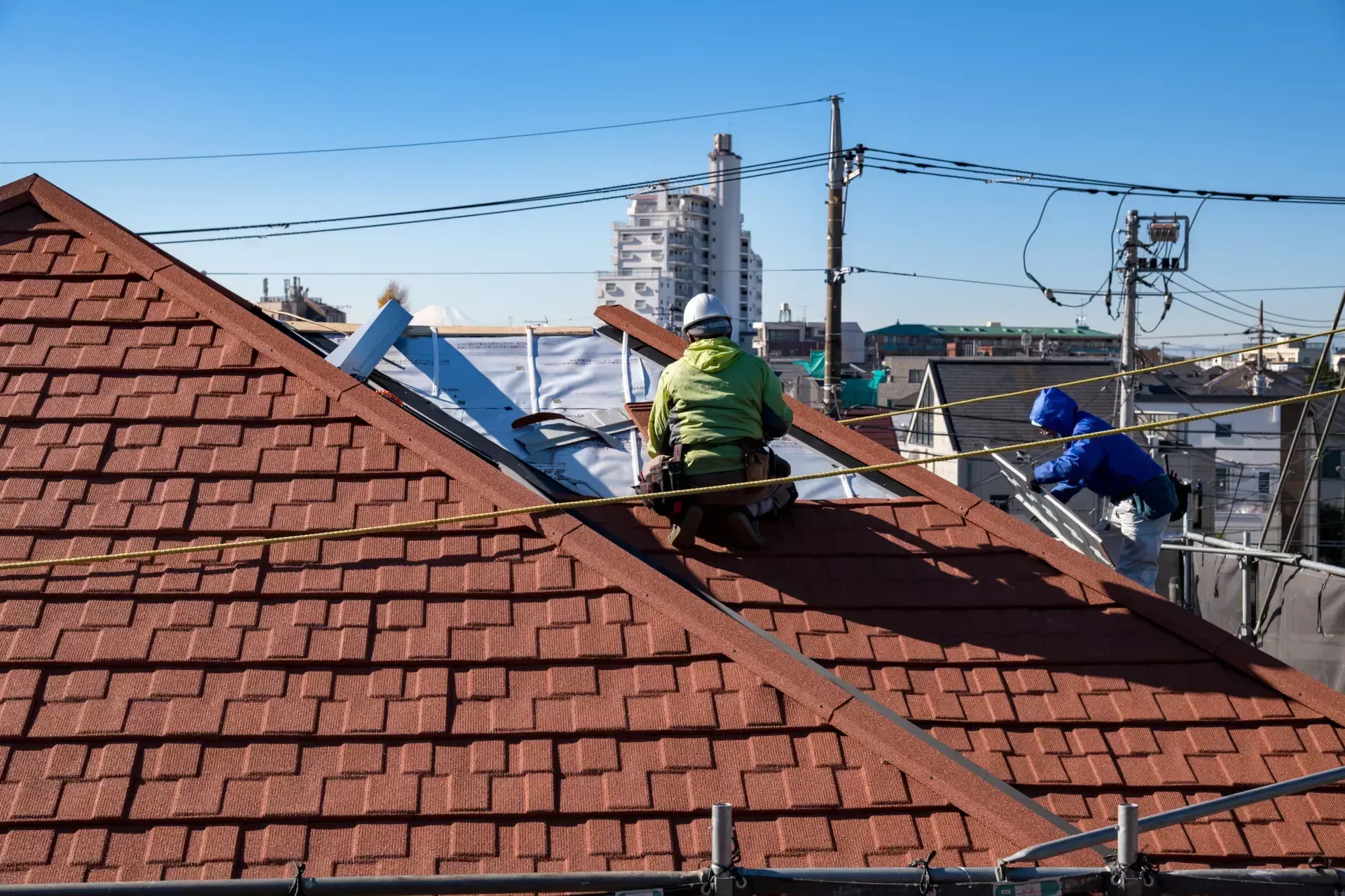 Two roofers are working on the roof of a building.