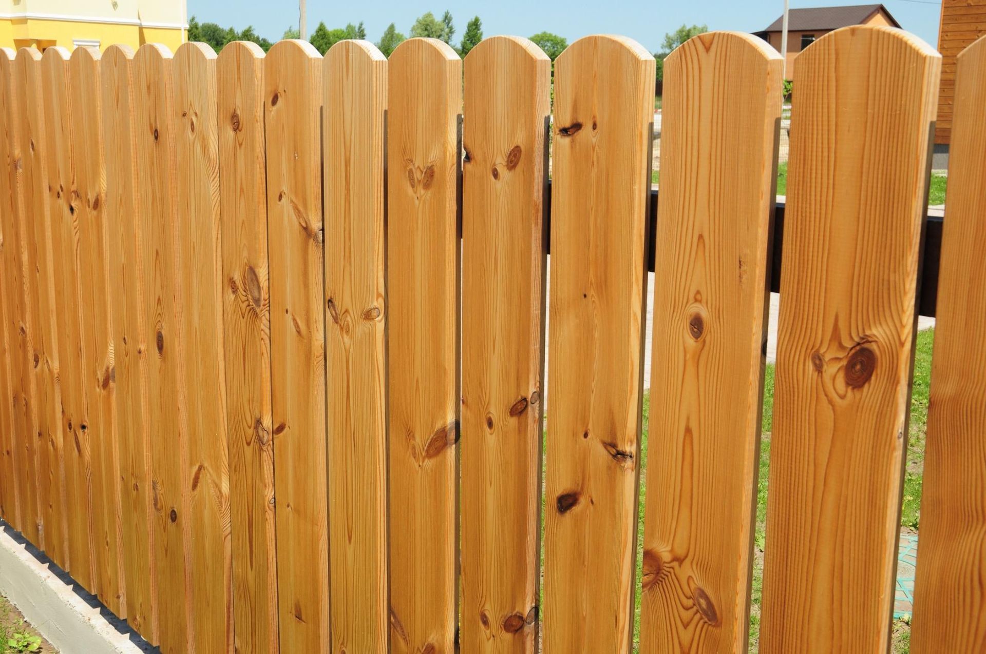 Wooden picket fence, tan color, outdoors in a yard.