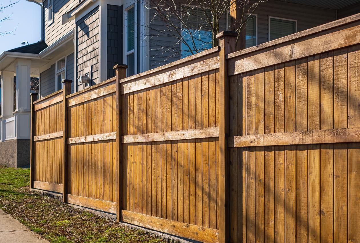 Wooden fence in front of a house, brown wood with vertical planks.