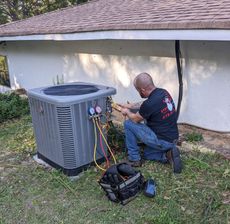 A man is working on an air conditioner outside of a house.