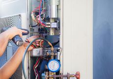 A man is working on an air conditioner with a screwdriver.