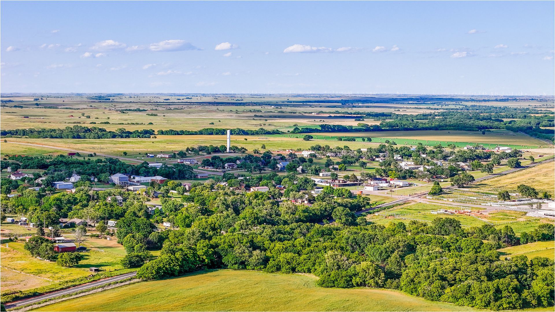 Aerial view of a small town nestled in a green valley, with fields and open plains stretching toward the horizon under a blue sky. Aerial view of a small town nestled in a green valley, with fields and open plains stretching toward the horizon under a blue sky.