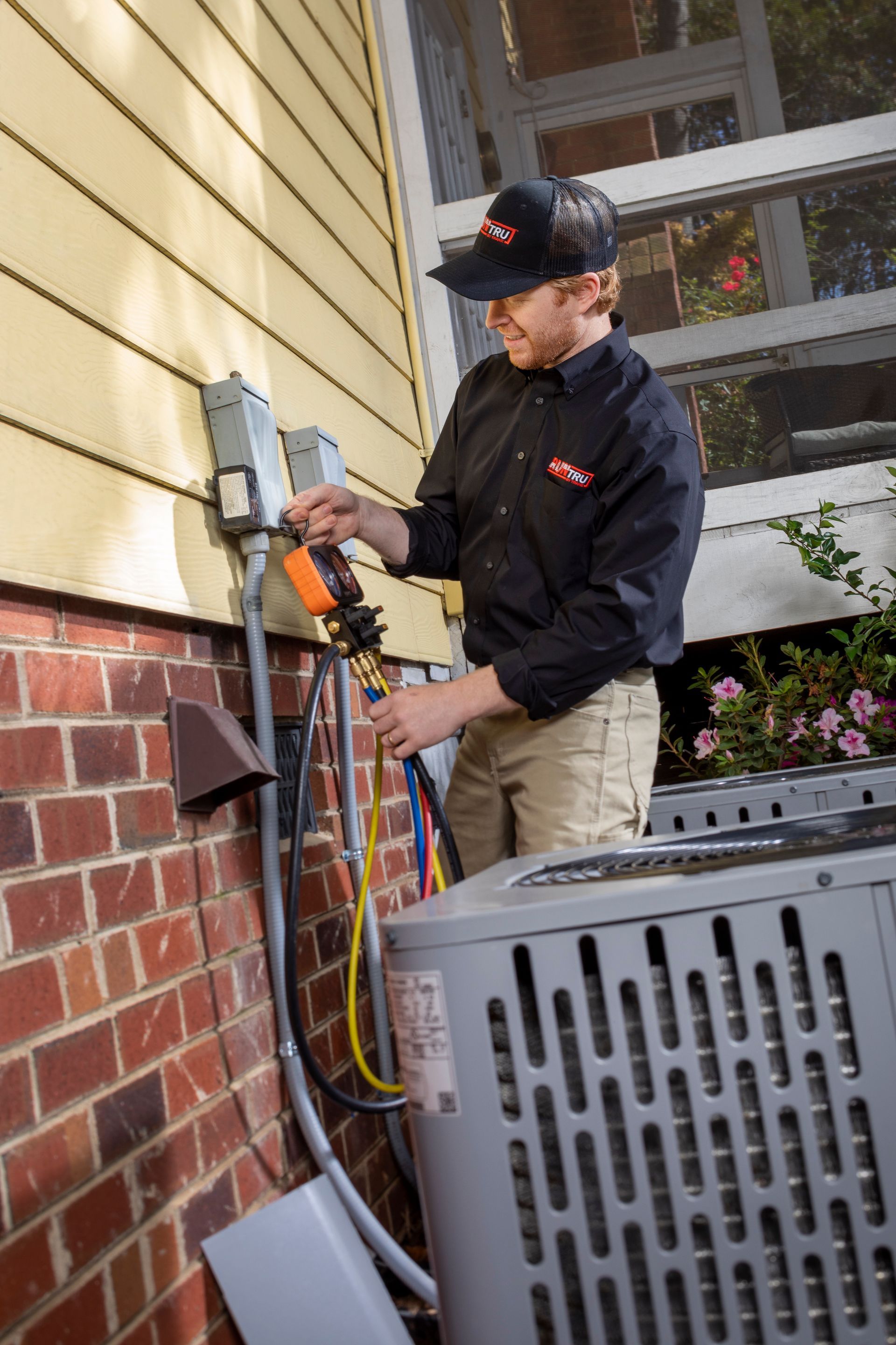HVAC technician in overalls and hard hat installing ceiling air conditioning unit.