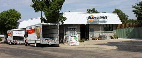 Store it WISE storage facility with two moving trucks parked in front.