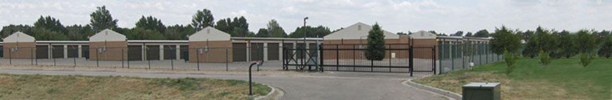 Storage facility with fenced perimeter and gate, overcast sky.