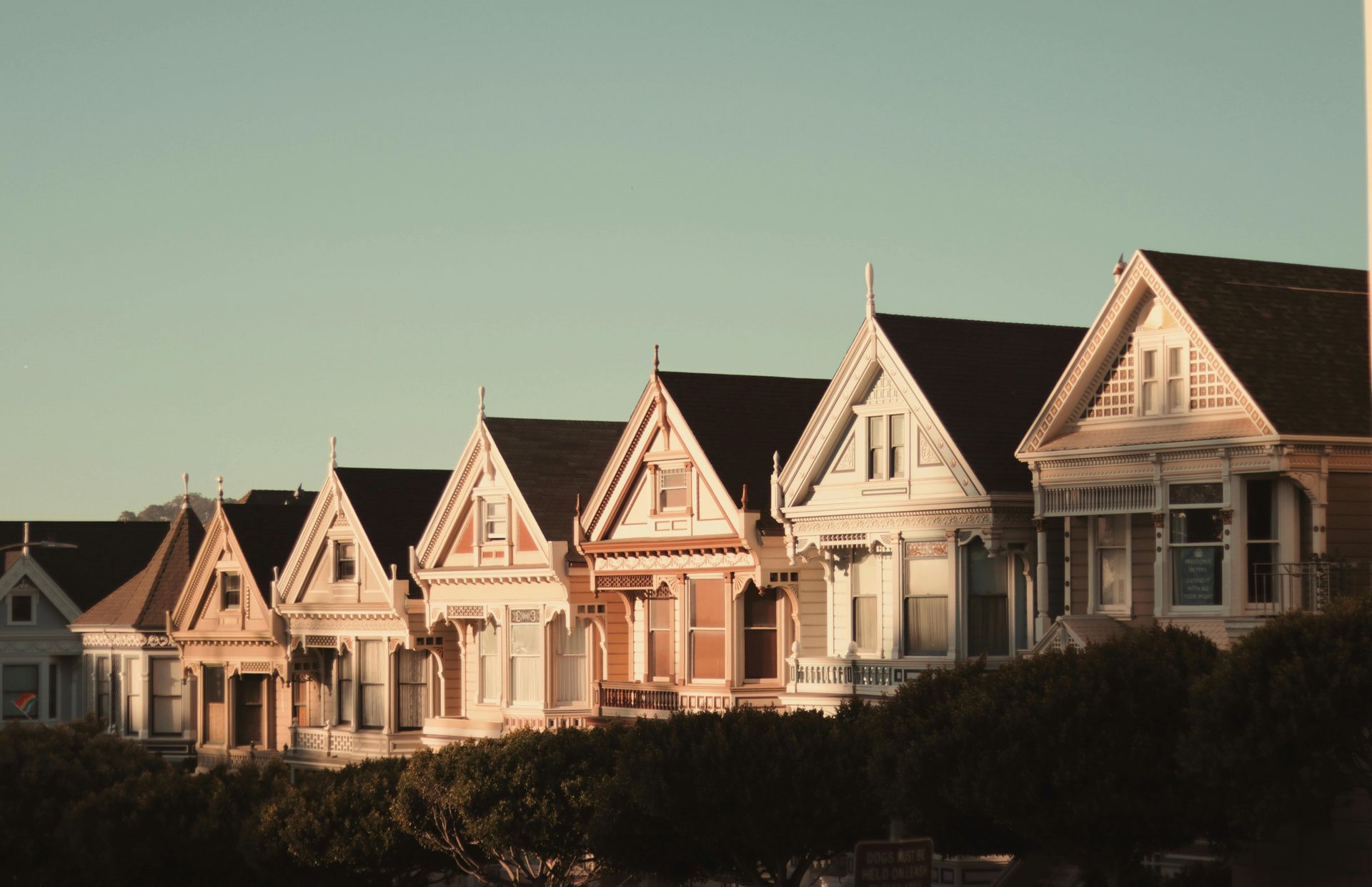 Row of colorful Victorian houses in San Francisco, bathed in golden sunlight.