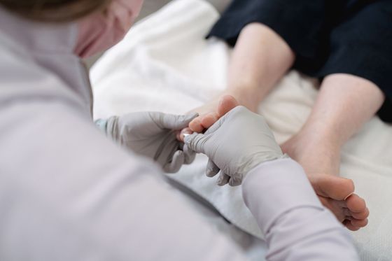 Podiatrist services treating patient foot with gloves during medical appointment.
