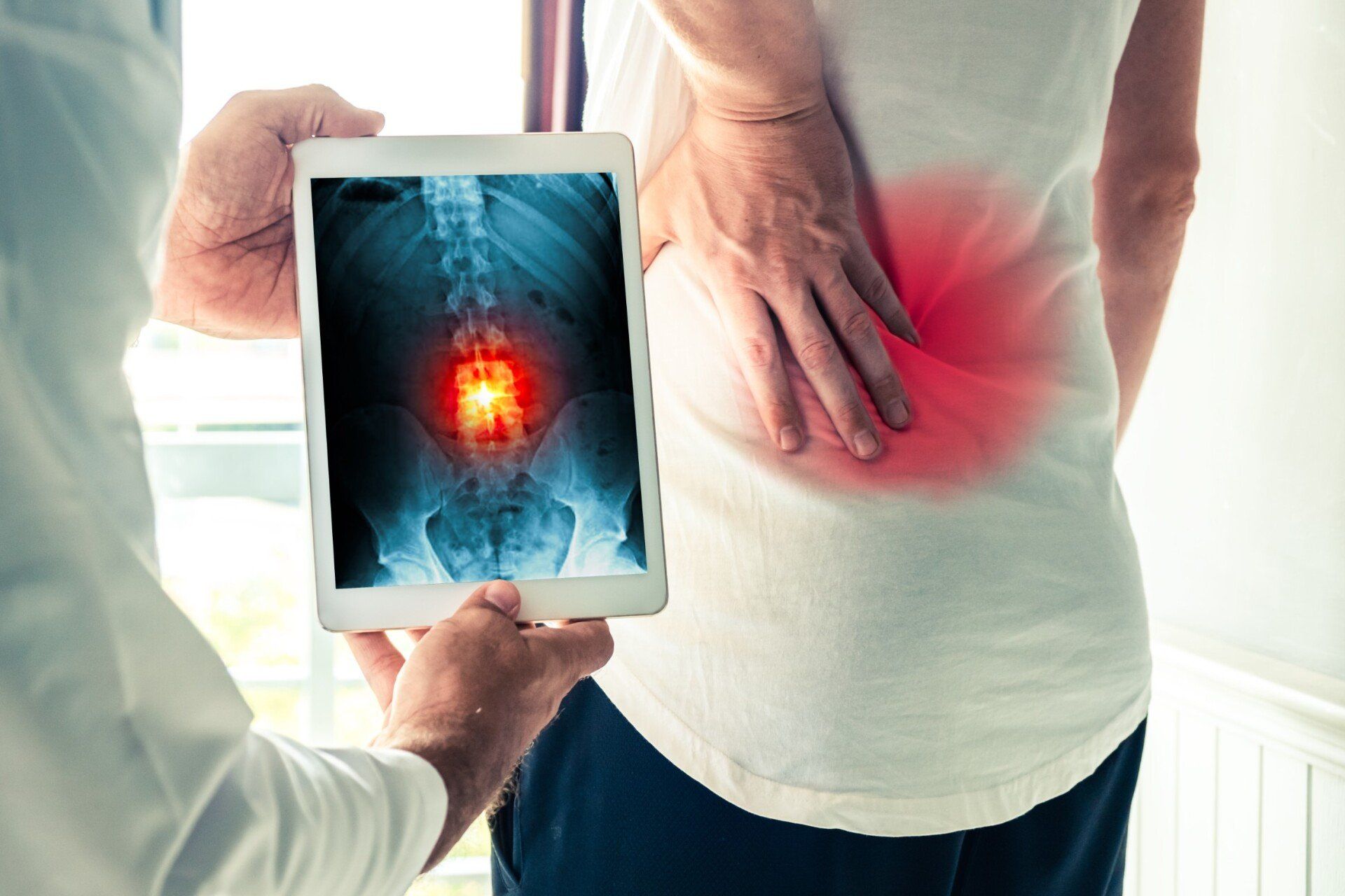 A doctor is holding a tablet with an x-ray of a person 's back.