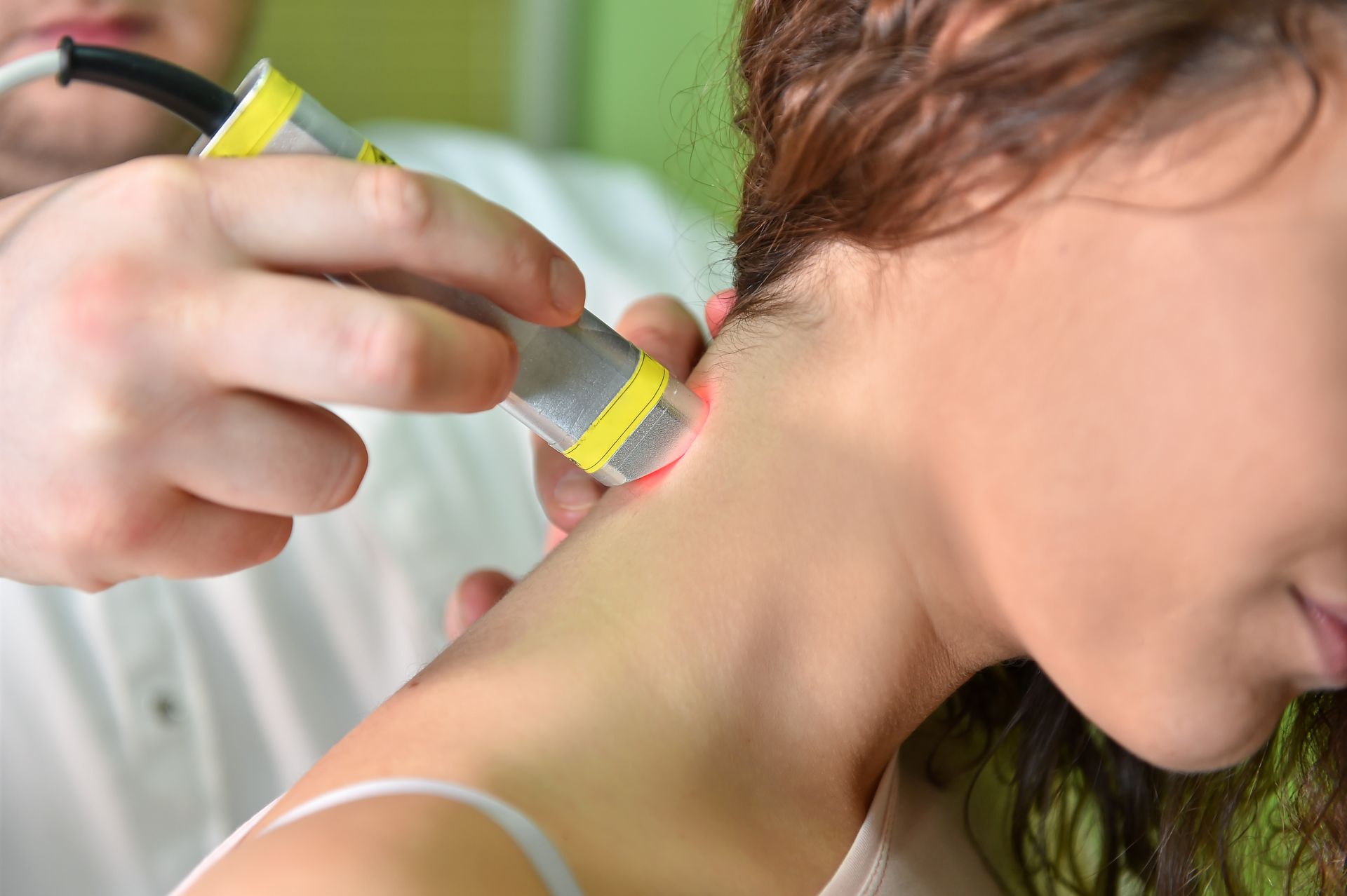 A woman is getting a laser treatment on her neck.
