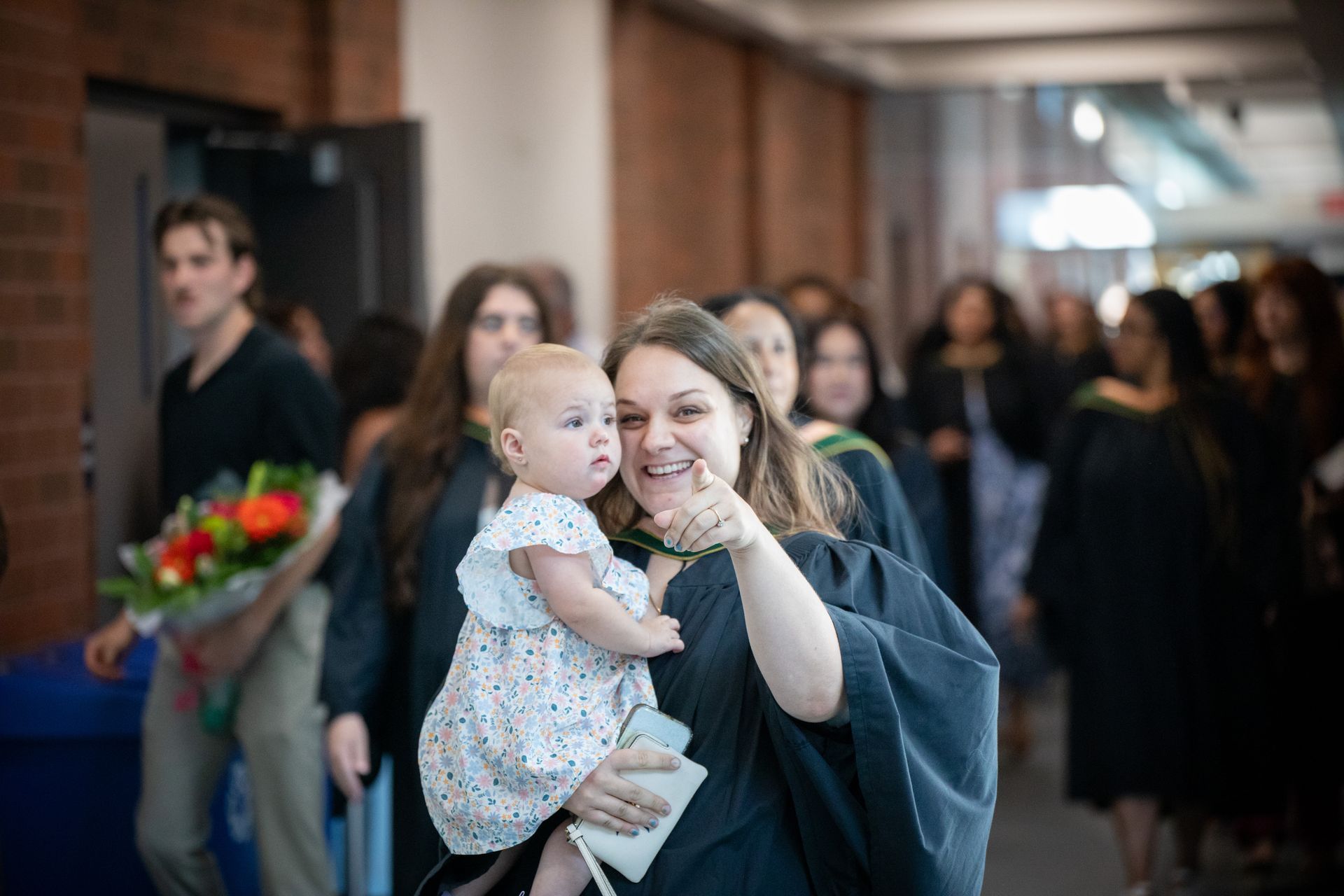 Graduate holding a baby and smiling