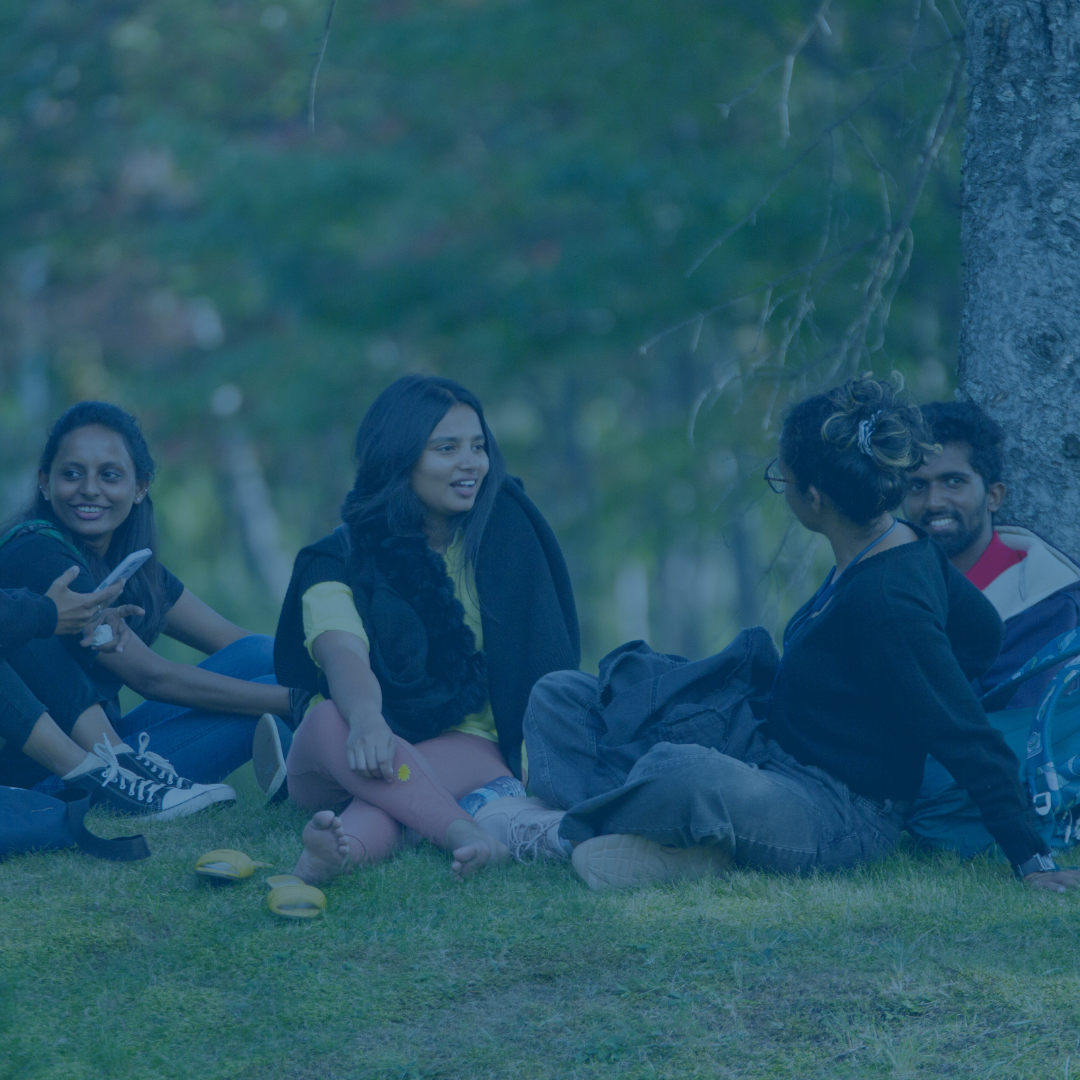 A group of students sitting outside and enjoying the sunshine.