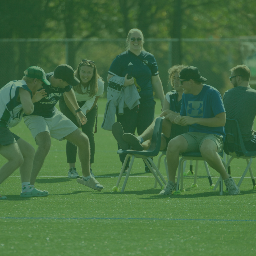 A group of students and coaches playing musical chairs.