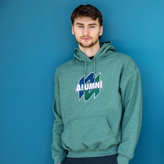 A man wearing a green hoodie that says alumni