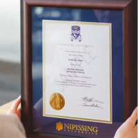 Framed Nipissing University diploma held by two hands.