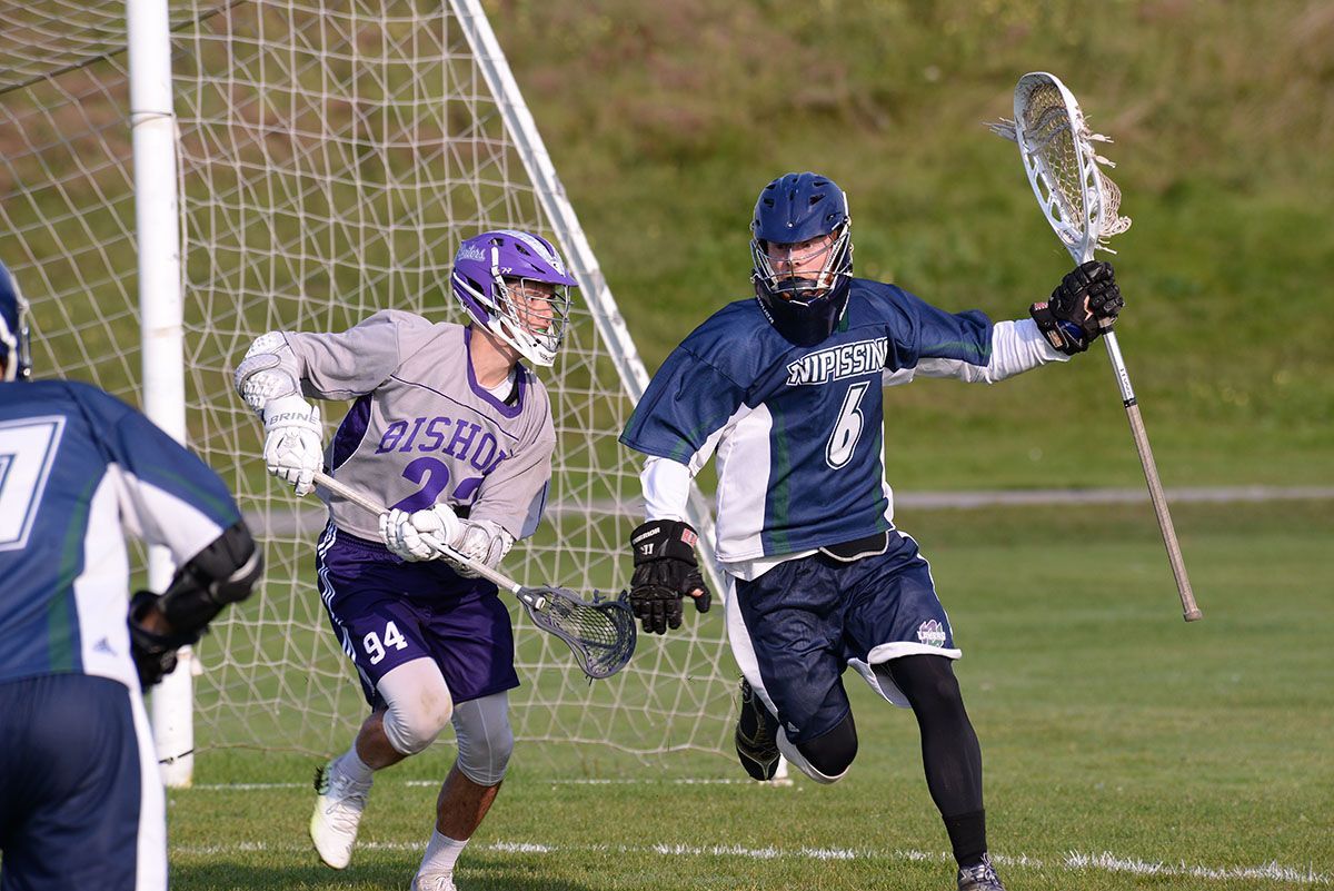 Two lacrosse players are playing a game of lacrosse on a field.