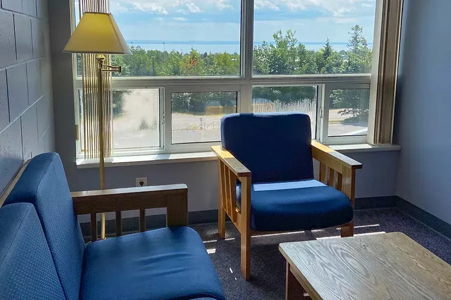 A living room with a couch , chair , table and lamp.