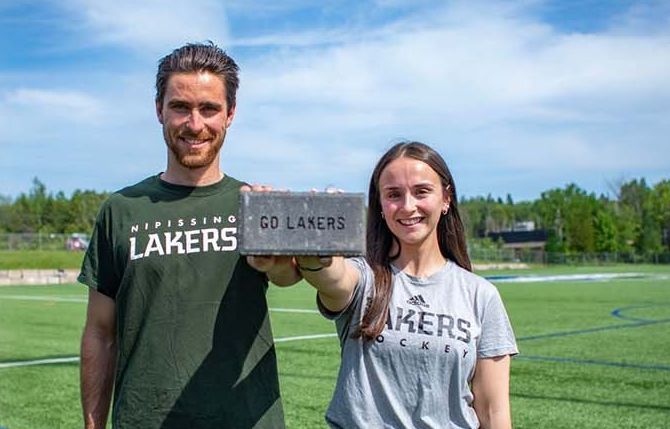 Two people hold a brick with