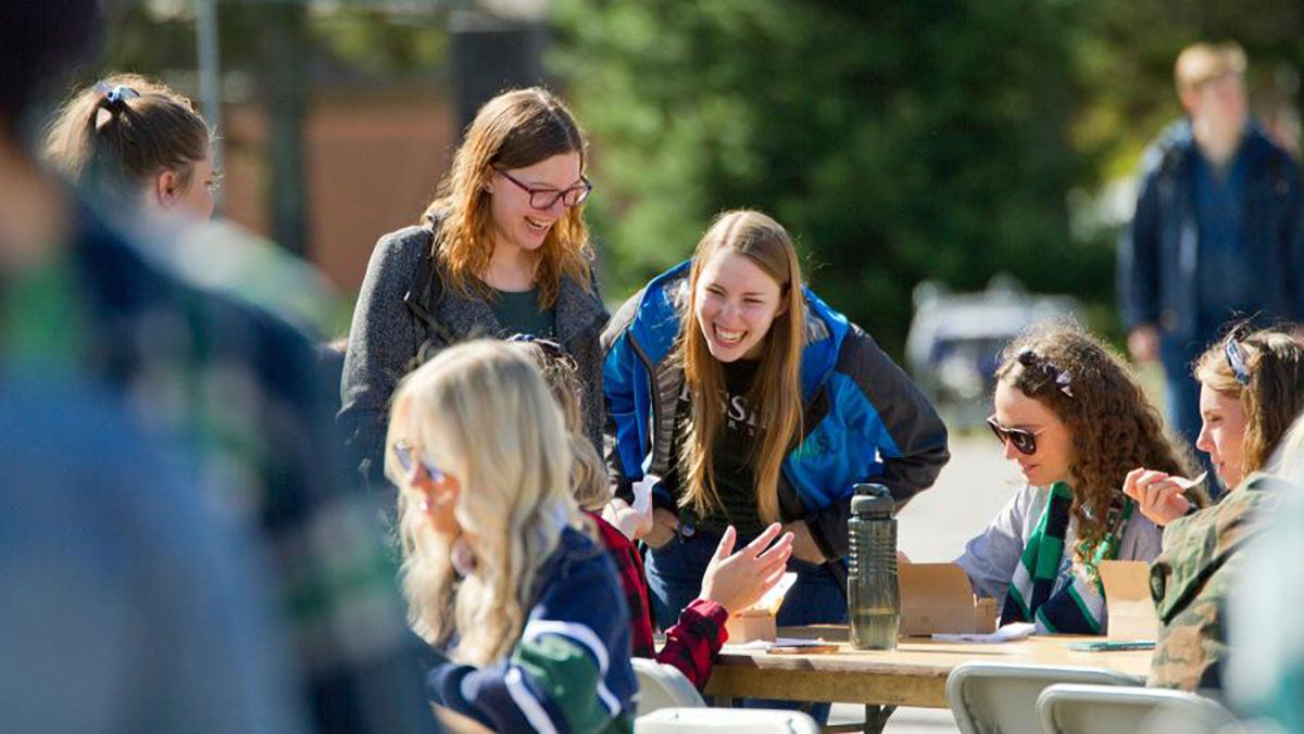 A group of young women are sitting at a table outside.