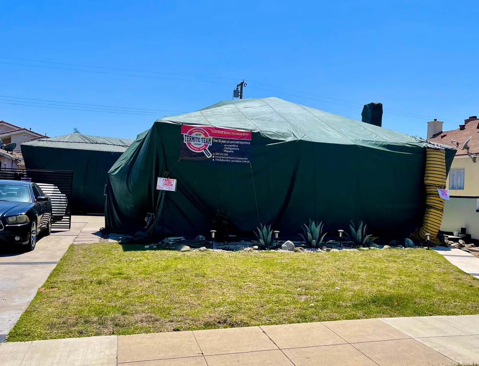 A green tarp is covering a house in a residential area.