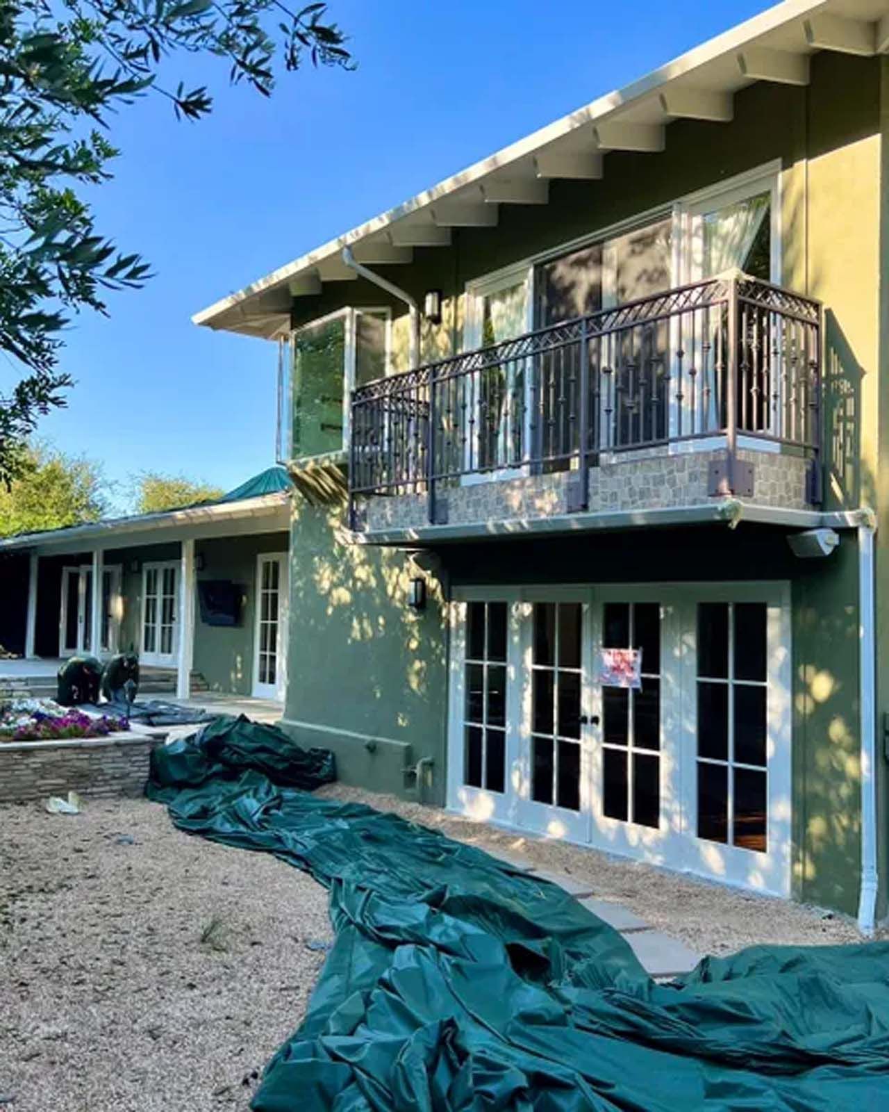 A large green house with a balcony is being painted.