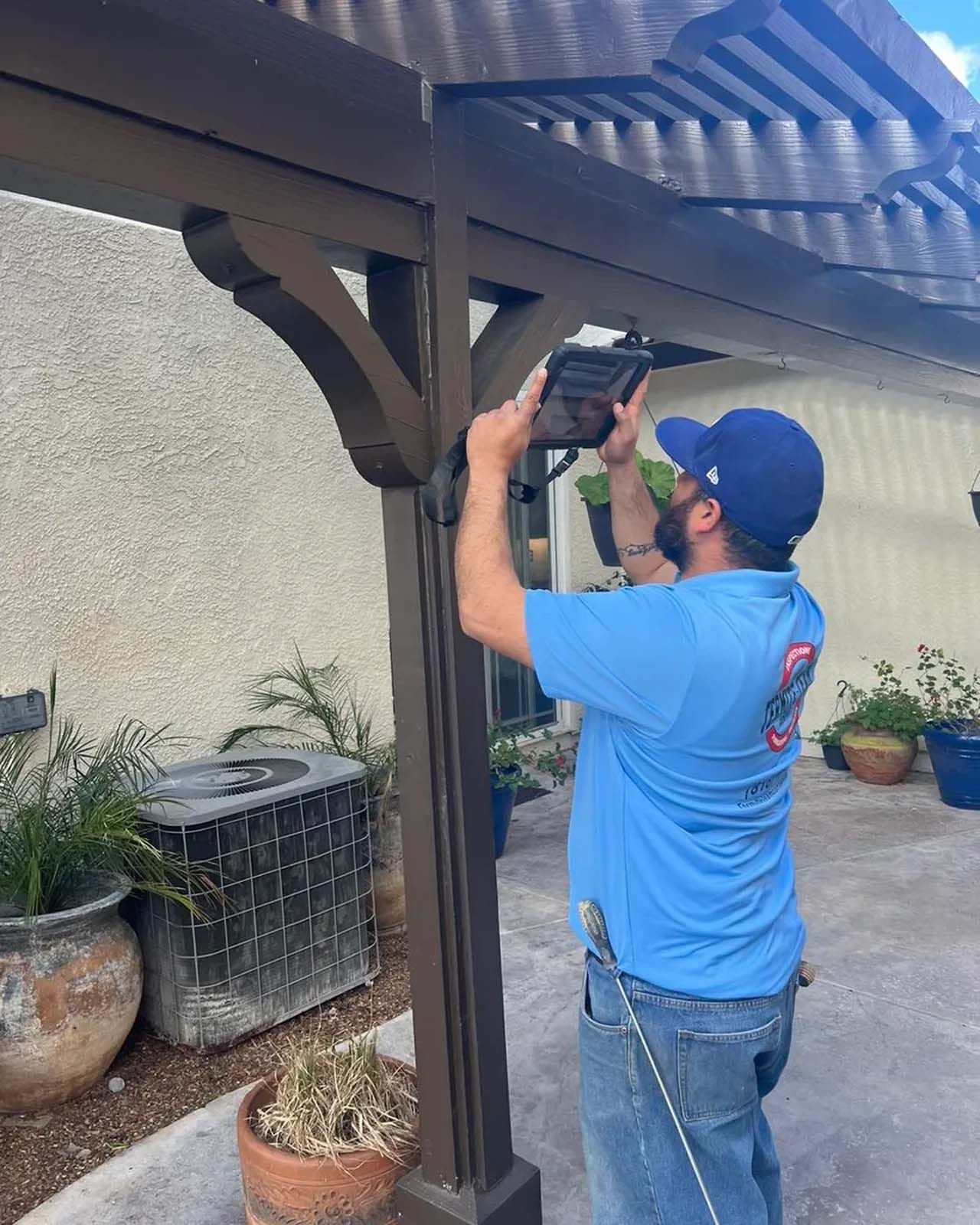 A man in a blue shirt is working on a pergola.