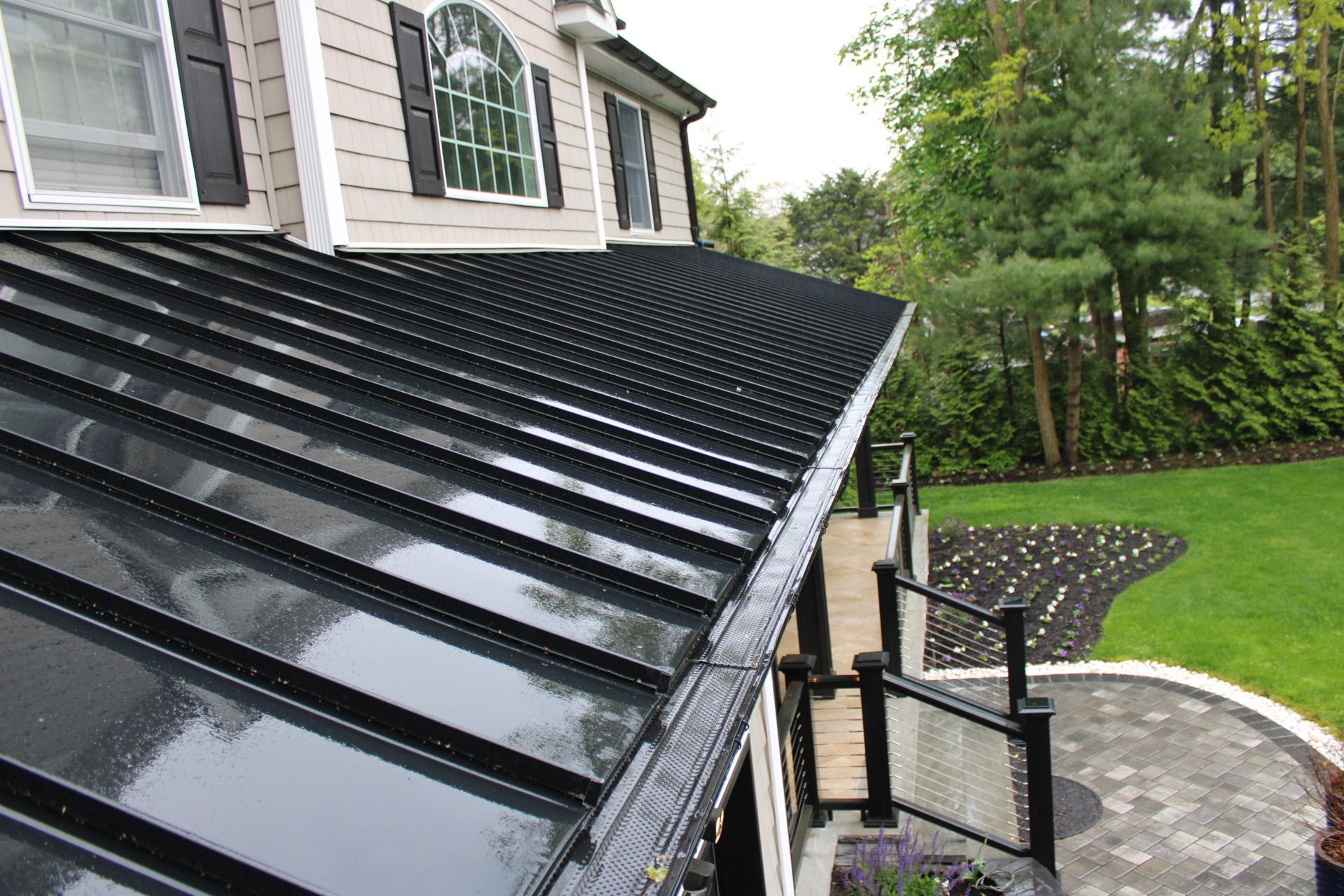 A house with a black roof and a patio in front of it