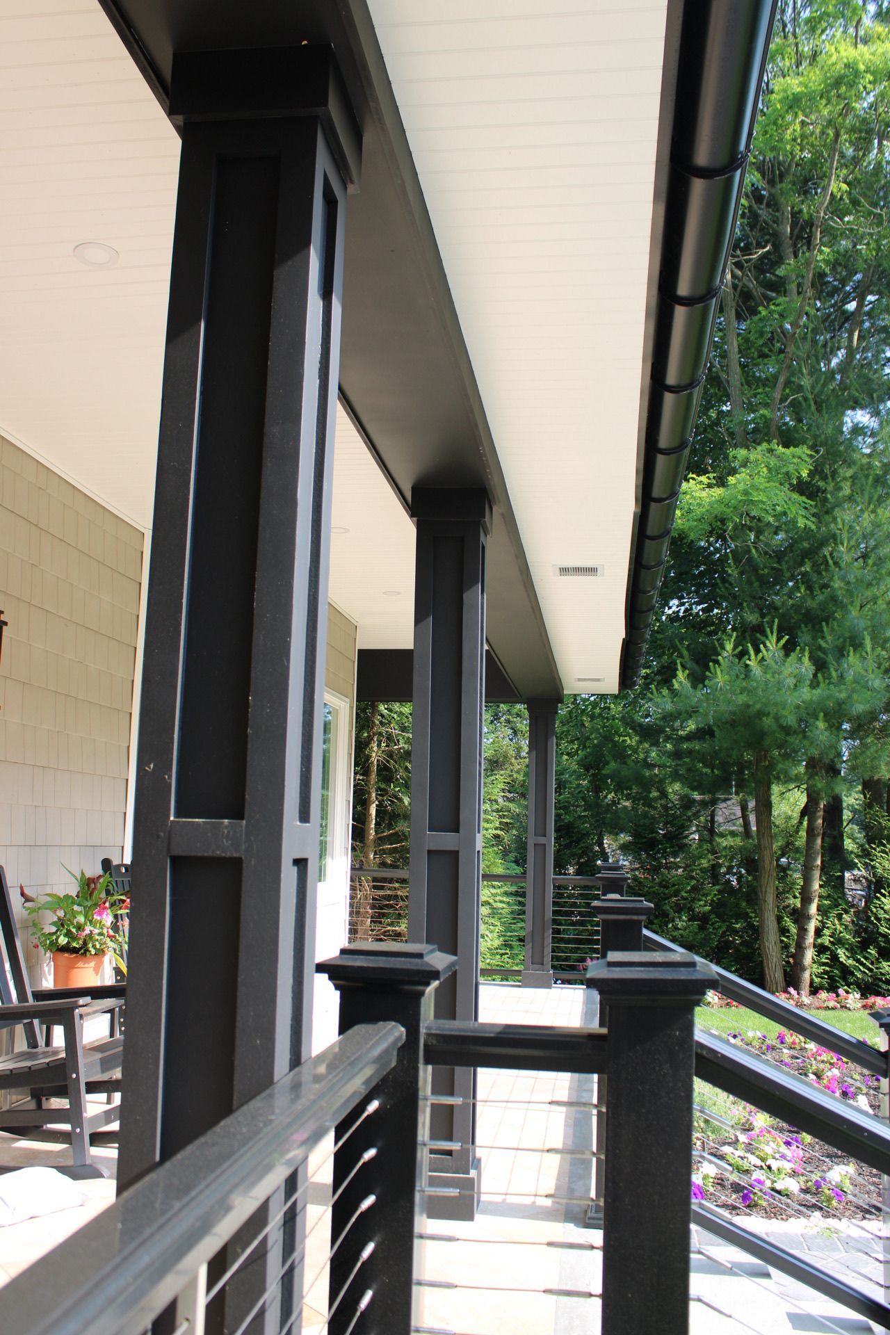 A porch with black columns and a white ceiling