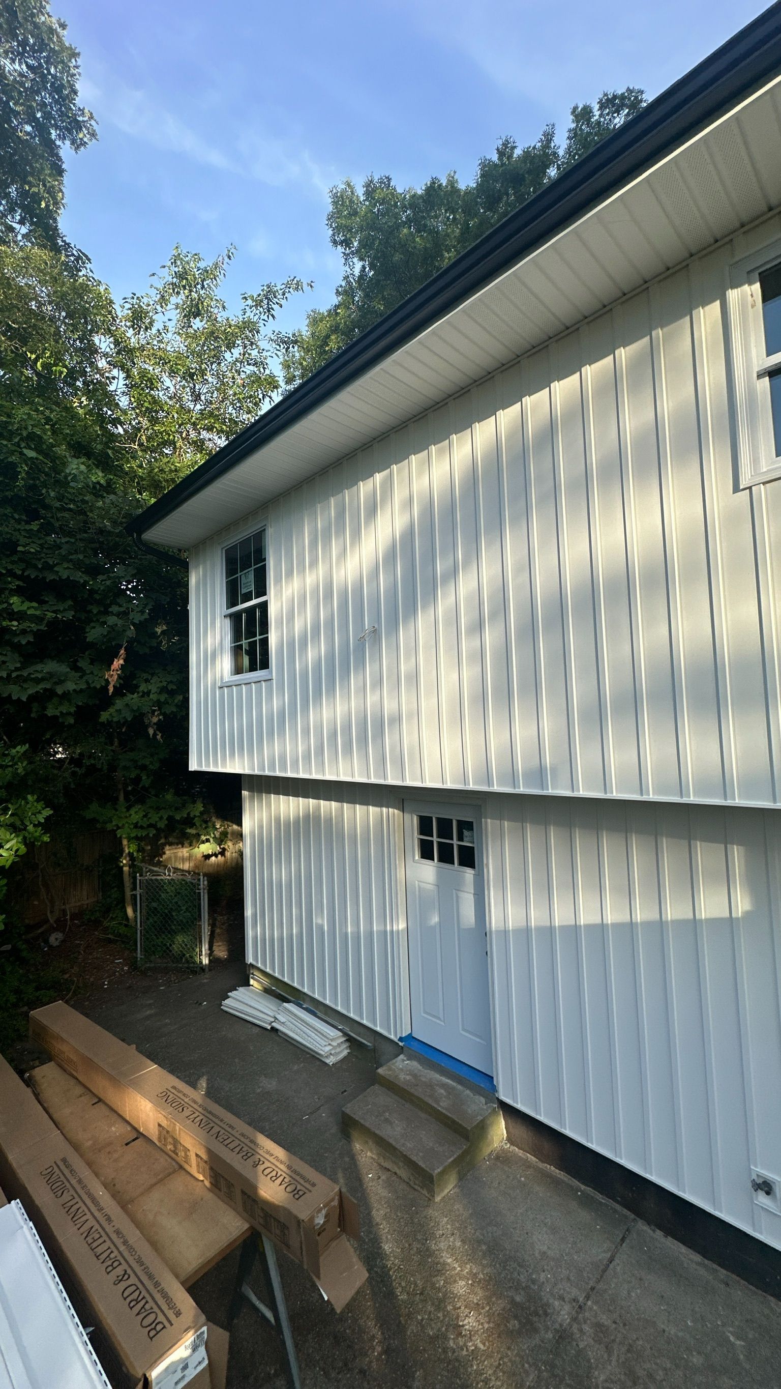 A white house with a black roof is being painted.